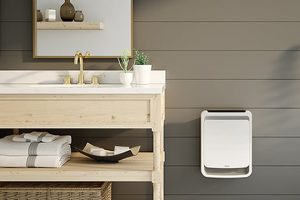 Appareil de chauffage mural de la marque Stelpro positionné à côté d'une vanité de salle de bain en bois naturel, avec lavabo blanc et robinetterie dorée